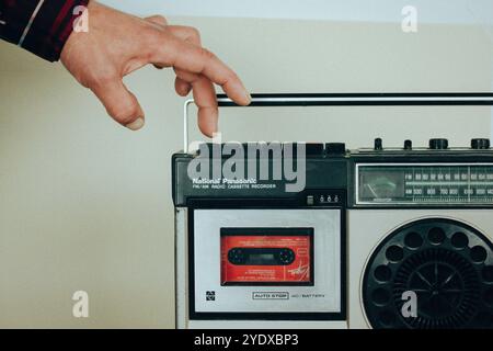 Madrid, Spanien. 2. Mai 2023 Ein Mann legte Musikkassette in einen alten Plattenspieler. Nostalgie für die 90er Jahre Vintage-Tonbandrecorder Ghetto Blaster Music Boom Box Stockfoto