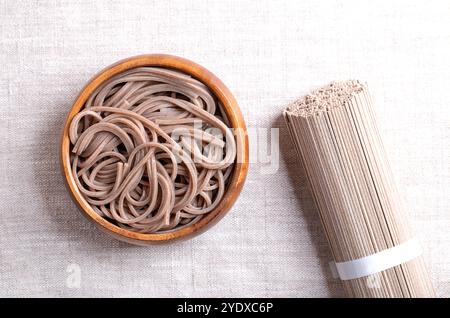 Gekühlte, gekochte Soba-Nudeln in einer Holzschale auf Leinenstoff. Dünne japanische Nudeln, die hauptsächlich aus Buchweizenmehl hergestellt werden, wobei Weizenmehl gemischt wird. Stockfoto