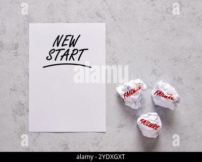 Aus Fehlern lernen. Bestimmung, Persistenz und Neuanfänge. Das Wort "New Start" steht auf einem weißen Blatt Papier mit zerknitterten Papieren mit Stockfoto