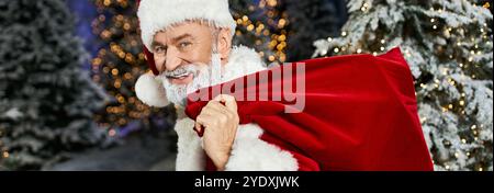 Eine fröhliche Figur trägt einen roten Sack, umgeben von einem Winterwunderland. Stockfoto