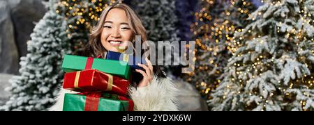 Ein lächelnder Mensch präsentiert wunderschön verpackte Geschenke in einem festlichen Weihnachtsgesang. Stockfoto