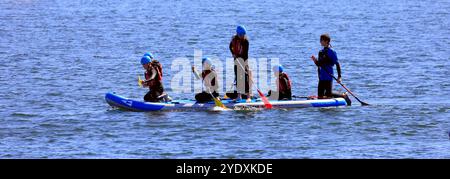 Paddelboardunterricht für Jugendliche in Sicherheitsausrüstung auf einem großen Paddelbrett, Lisvane & Llanishen Stauseen, Sommer 2024 Stockfoto