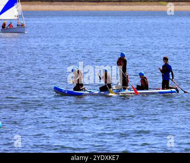 Paddelboarding und Segelunterricht für Jugendliche in Sicherheitsausrüstung auf einem großen Paddelbrett, Lisvane & Llanishen Stauseen, Sommer 2024 Stockfoto