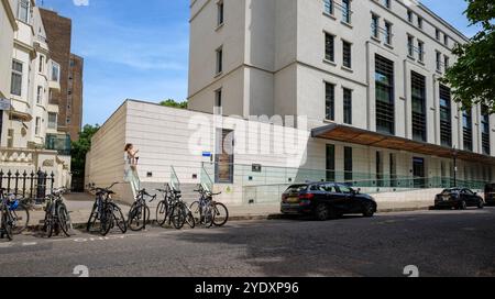 London - 06 16 2022: Mädchen schaut sich das Smartphone vor dem Ethos Sports Centre an Stockfoto