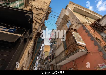 Neapel, Italien - 23. Mai 2024: Pulsierende urbane Alley in Neapel, Italien, mit Wäscheleinen zwischen hohen, verwitterten Gebäuden, Drähten und A Stockfoto