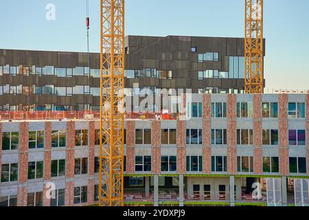 Zwei große Turmkräne auf der Baustelle vor klarem blauem Himmel. Modernes Gebäude in Entwicklung. Skandinavische Architektur im Bau Stockfoto