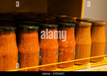 Verschiedene Gläser gefüllt mit köstlicher Tomatensoße sind ordentlich organisiert und auf einem Regal im Kühlschrank angeordnet, um den Zugang zu erleichtern Stockfoto