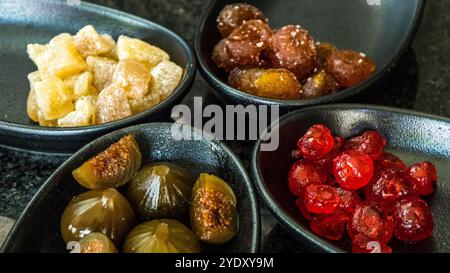 Fruchtmedley verschiedener kandierter Früchte in schwarzen Wüstenschalen Stockfoto