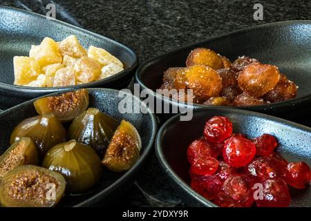 Fruchtmedley verschiedener kandierter Früchte in schwarzen Wüstenschalen Stockfoto