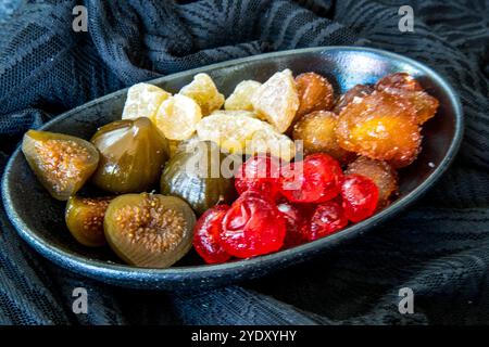 Schwarze Dessertschüssel gefüllt mit einem Medley mit konservierten Früchten auf weichem schwarzem Material Stockfoto
