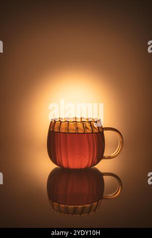 Kreative Fotografie in transparentem Becher mit Tee, warme orange Farben, mit Kopierraum, Komposition Stillleben Stockfoto