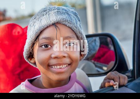 afrikanisches Dorfmädchen wartet am Autofenster und fragt nach dem Weg, Blick von innen Stockfoto