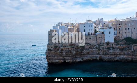 Das malerische Dorf Polignano a Mare Italien verfügt über weiß getünchte Gebäude auf dramatischen Klippen, mit Blick auf das atemberaubende blaue Wasser der Adria unter hellem Himmel. Stockfoto