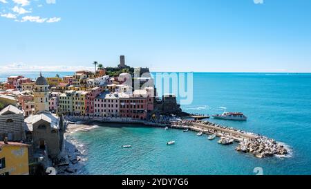 Schlendern Sie durch die malerische Küste von Cinque Terre, wo sich pulsierende Häuser an felsigen Klippen mit Blick auf das glitzernde Meer Klammern. Touristen genießen einen sonnigen Tag voller Entdeckungen und Wunder. Stockfoto