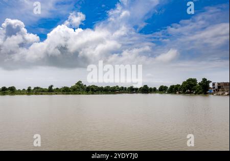 Überflutetes Flussufer mit hellblauem Himmel am Morgen Stockfoto