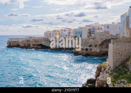 Das türkisfarbene Wasser an der Küste Apuliens, wo alte Klippen auf lebendige Gebäude treffen, tanzen glitzernde Sonnenstrahlen. Polignano a Mare Italien Stockfoto