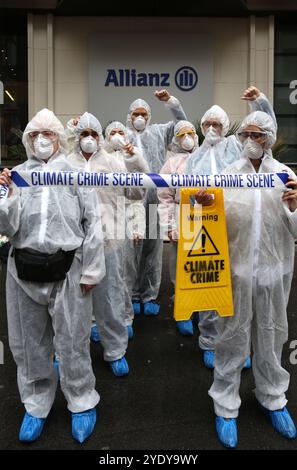 London, England, Großbritannien. Oktober 2024. Demonstranten in Gefahrgutanzügen, Masken und mit Tatortband protestieren vor den Büros der Allianz-Versicherungsgesellschaft. Extinction Rebellion (XR) spazieren Sie durch die City of London, halten Sie an und demonstrieren Sie vor den Büros von Versicherungsunternehmen, die trotz der Warnungen vor einer Klimakrise von Wissenschaftlern weiterhin Unternehmen für fossile Brennstoffe versichern. Die Demonstranten glauben, wenn die Versicherungsgesellschaften ihre Beteiligung an diesen Unternehmen beenden würden, würden sie es schwer tun, weiter zu bauen. Die Aktion ist die erste einer Woche lang, die sich speziell gegen t richtet Stockfoto