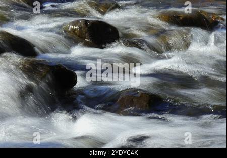 Umgebung. Schnell fließendes kristallklares Wasser fließt durch Felsen in einem großen Bach. Jamor River. Oeiras, Portugal. Fotografische Techniken - Langzeitbelichtung Stockfoto