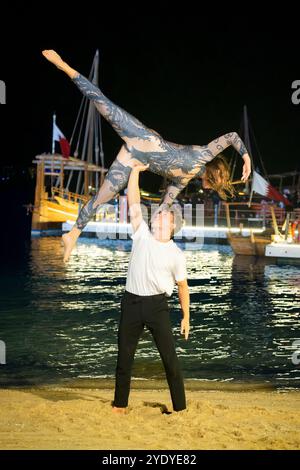 Ein Paar spielt eine elegante Gymnastik-Pose in Kataras Katara Fan Zone und verleiht der FIFA-Atmosphäre Anmut. Stockfoto