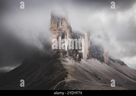 Eine hoch aufragende Klippe von Tre Cime di Lavaredo ragt durch niedrige Wolken und schafft eine dramatische und unheimliche Szene in den italienischen Dolomiten. Stockfoto