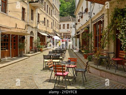 Tische von einer Bar säumen die Straßen und warten auf Gäste. Im Gjirokaster Basar, einem historischen Marktplatz, der für seine erhaltene osmanische Architektur bekannt ist Stockfoto