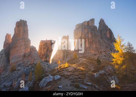 Das Morgenlicht beleuchtet die zerklüftete, goldene Lärchenlandschaft der Cinque Torri in den italienischen Dolomiten und schafft eine ruhige und dennoch dramatische Herbstszene. Stockfoto