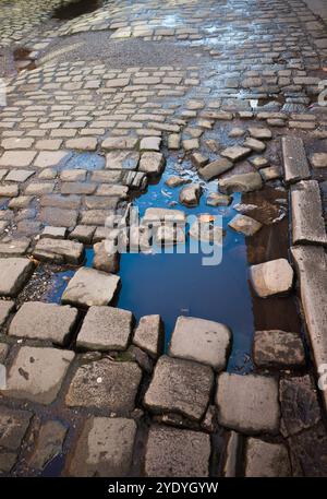 Eine alte Kopfsteinpflasterstraße mit fehlenden und gebrochenen Steinen. Stockfoto