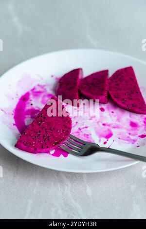 Scheiben von Drachenfrüchten auf einem weißen Teller mit einer Gabel. Stockfoto