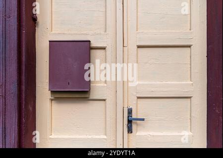 Eine bezaubernde gelbe Holztür mit Briefkasten in einer malerischen Gegend tagsüber Stockfoto