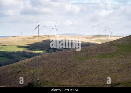 Stromleitungsmasten und Windturbinen stehen auf dem Mynydd y Betws Mountain in der Nähe von Swansea in Südwales. Stockfoto