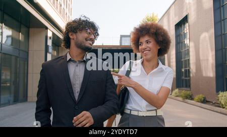Unternehmen vielfältige multirassische Kollegen Kollegen in der Stadt draußen zu Fuß zu Fuß zu sprechen nach der Arbeit verlassen das Büro des Unternehmens zu Fuß indischer Mann Geschäftsmann mit Stockfoto