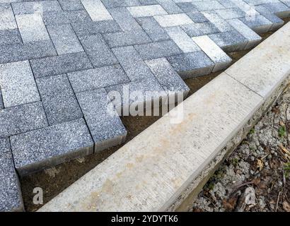 Annäherung von Pflasterplatten an die Bordsteinkante bei Verlegung im Fischgrätenmuster Stockfoto