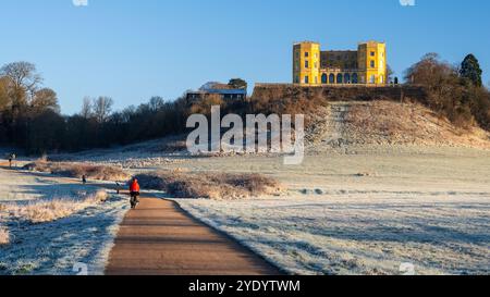 Radfahrer und Fußgänger fahren an einem frostigen Morgen in Bristol, England, auf einem Pfad durch den Stoke Park, unter dem „Yellow Castle“-Dower House. Stockfoto