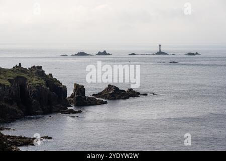 Die Sonne scheint auf den Klippen am Land's End von Cornwall, mit Langlauffelsen in der Ferne. Stockfoto