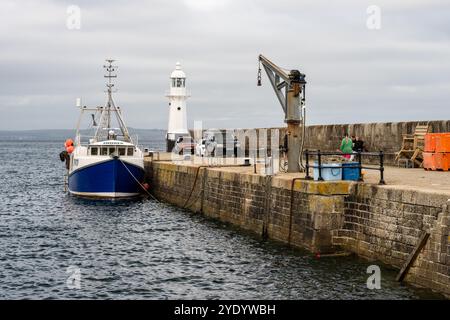 Ein Fischerboot liegt an der Außenmauer des Mevagissey Harbour an der Küste von Cornwall, England. Stockfoto