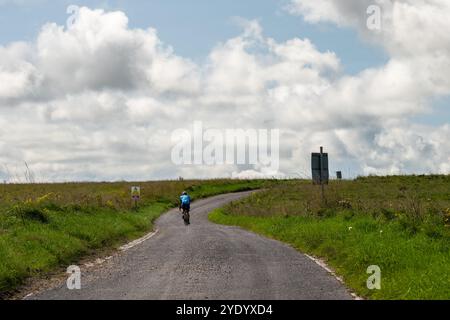 Ein Rennradfahrer bestieg einen Hügel im Trainingsgebiet der Imber Range British Army auf der Salisbury Plain in Wiltshire. Stockfoto