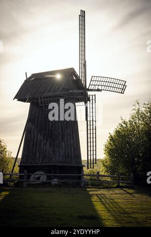 Silhouette einer alten hölzernen Windmühle bei Sonnenuntergang. Vertikales Foto. Michailowskoje, Bezirk Puschkinogorski des Oblast Pskow, Russland Stockfoto