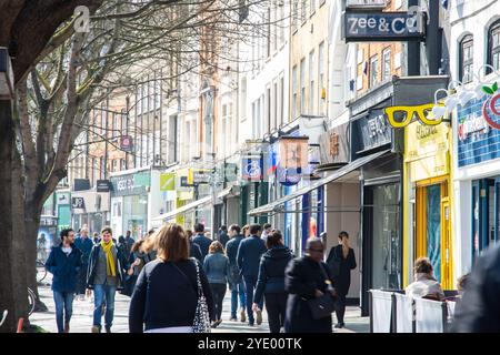 Fußgänger und Shopper laufen an Geschäften und Dienstleistungen auf der traditionellen High Street in der Upper Street in Islington, London vorbei. Stockfoto