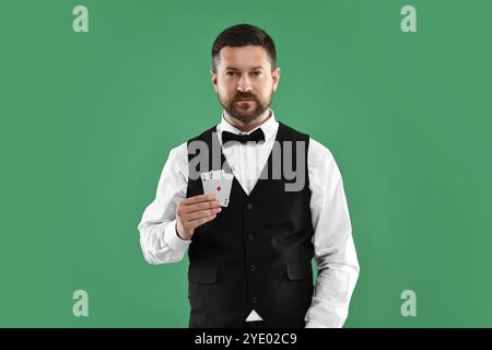 Professioneller Croupier mit Spielkarten auf grünem Hintergrund Stockfoto