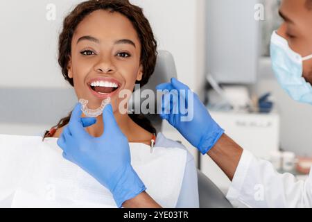 Zahnarzt, der unsichtbare Ausrichter auf die Zähne eines weiblichen Patienten anwendet Stockfoto