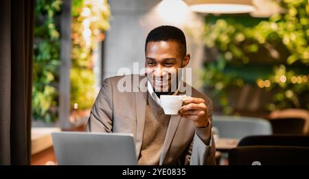 Schwarzer Kerl, der eine Tasse Kaffee im Büro hält Stockfoto