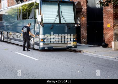 Knoxville, TN, USA-21 Sept. 2024: Mann schließt ein Ablagefach eines Prevost Tourbusses ab, an der Seite des Bijou Theaters. Stockfoto