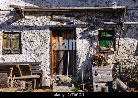 Altes rustikales Steinhaus mit Holztür und grünen Fensterläden in einer ruhigen ländlichen Gegend bei Tageslicht Stockfoto