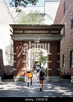 Knoxville, TN, USA-21 Sept. 2024: Drei junge Frauen mit langen silberblonden Haaren gehen durch den Torbogen und verlassen den Market Square. Stockfoto