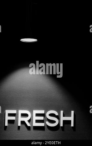 „Fresh“ in Lights: Beleuchtetes Wort auf der Cafeteria-Wand mit einem filmischen Leuchten Stockfoto