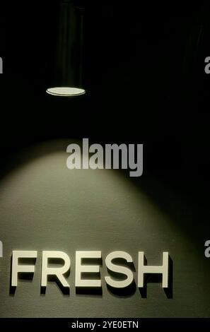 „Fresh“ in Lights: Beleuchtetes Wort auf der Cafeteria-Wand mit einem filmischen Leuchten Stockfoto