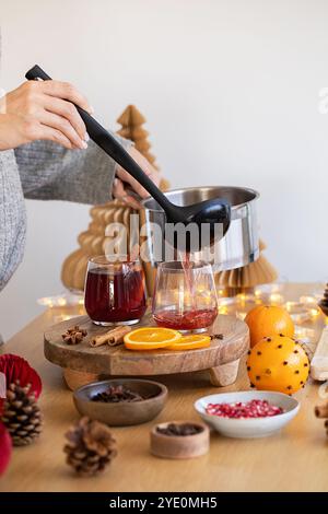 Eine gemütliche Urlaubsszene mit Glühwein, der auf einem festlichen Tisch in Gläser gegossen wird. Stockfoto