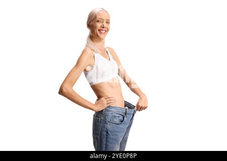 Glückliche schlanke Frau, die eine Jeans anzieht und die Kamera auf weißem Hintergrund lächelt Stockfoto