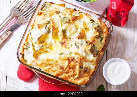 Traditionelle bulgarische oder Balkantorte Banitsa aus Filo-Teig, Frischkäse und Spinat, serviert mit Sahne und Kaffee auf hölzernem Hintergrund. Rustikal Stockfoto