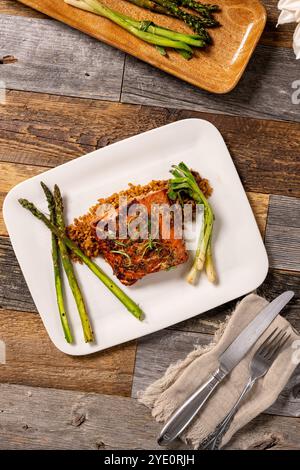 Überzogene Mahlzeit aus Ahornfilet mit Lachsfilet auf einem Bett aus würzigem Reis mit gegrilltem Spargel. Stockfoto